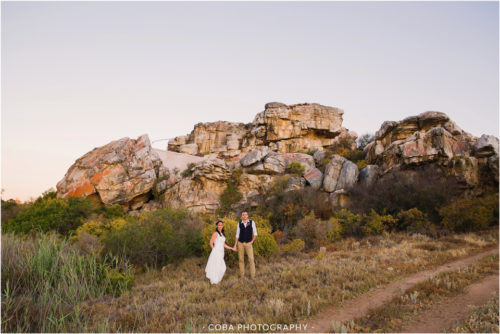 wedding coulple in front of rock formations at bosduifklip
