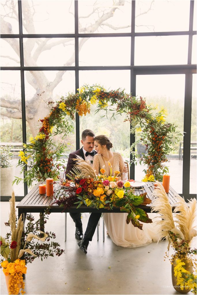wedding couple at table of colourful decor at the conservatory