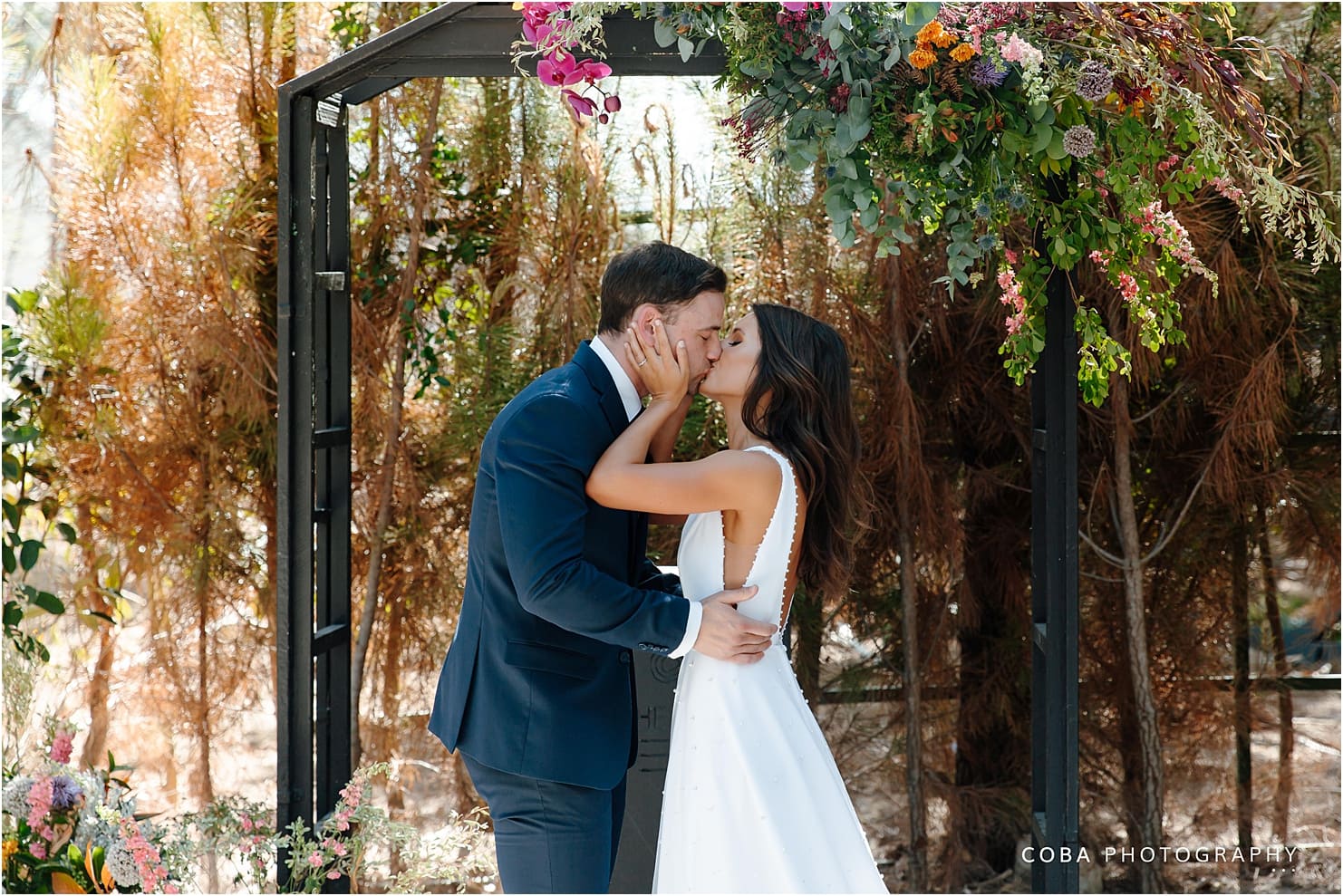 the one heaven and earth wedding - brin and kath - couple kissing underneath arch