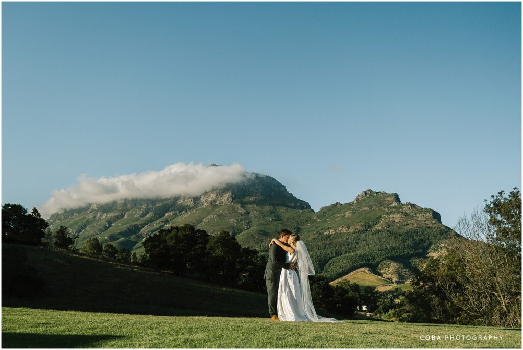 alluvia wedding venue - regert and annami - couple with mountain background in stellenbosch