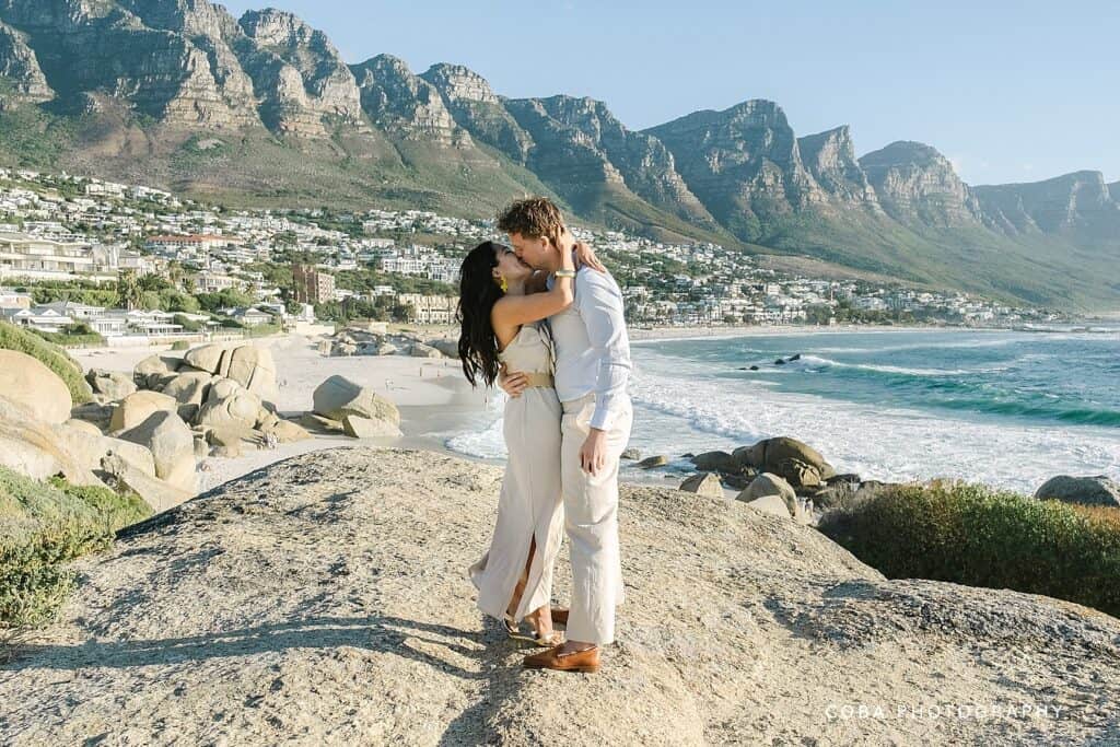 Newly engaged couple embracing during a Camps Bay sunset proposal at the iconic Maiden’s Cove lookout.
